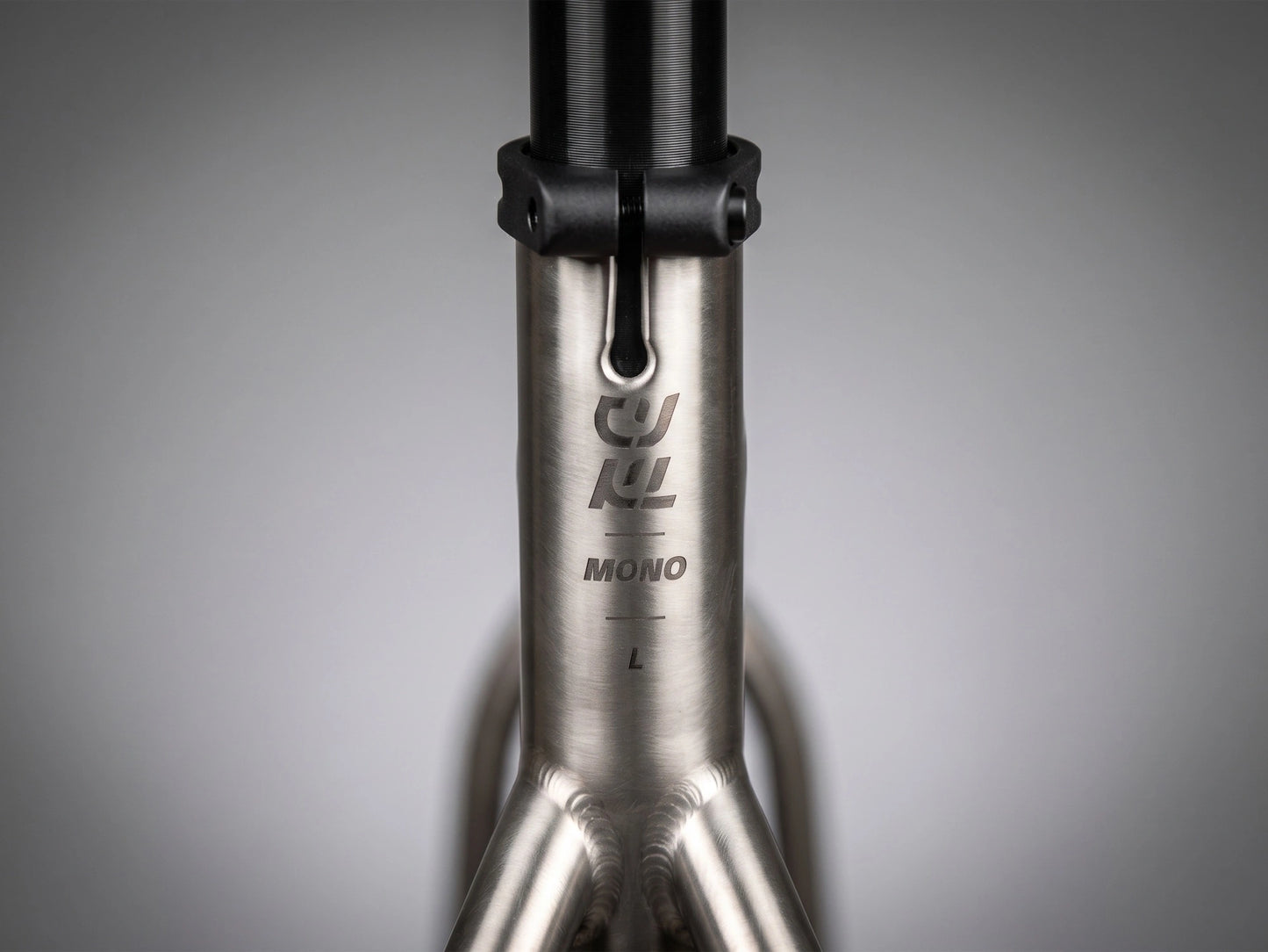 Détail du tube de selle en titane brossé du CYKL MONO, montrant le marquage gravé et l'indicateur de taille L, illustrant la finition minérale du Grade 9.