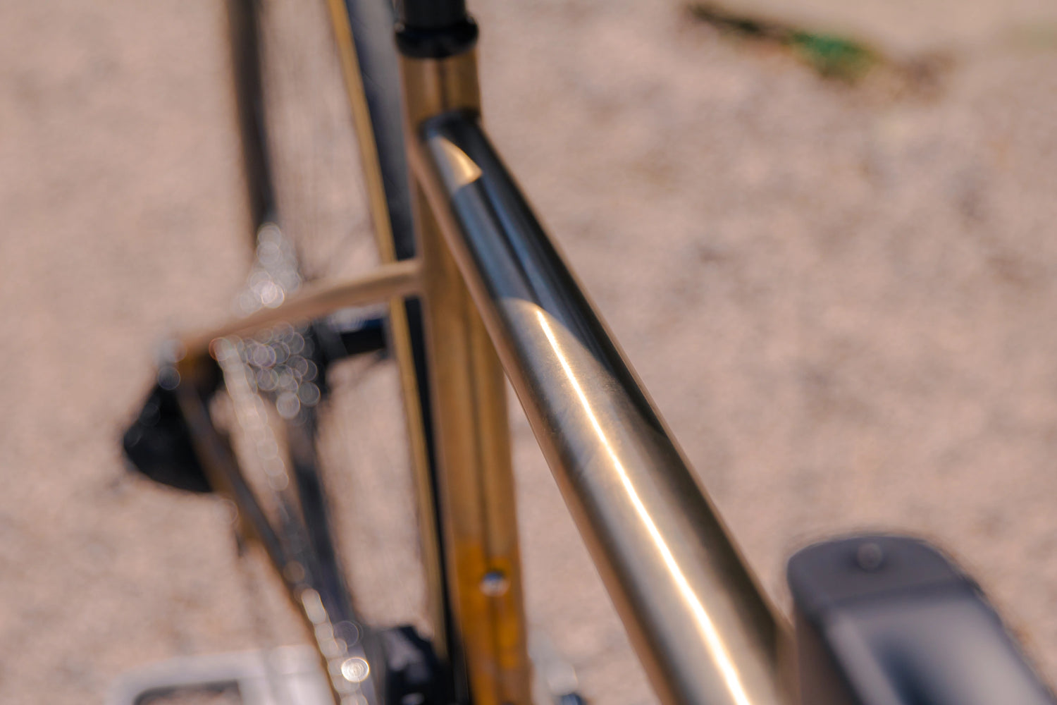 Gros plan sur la finition brossée et l'anodisation bronze sur mesure du tube supérieur du cadre titane CYKL SWIIFT.