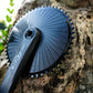 Plateau Stone Aero noir monté sur une manivelle SRAM Force AXS, appuyé contre une roche en extérieur avec des feuilles vertes, vue en plongée.
