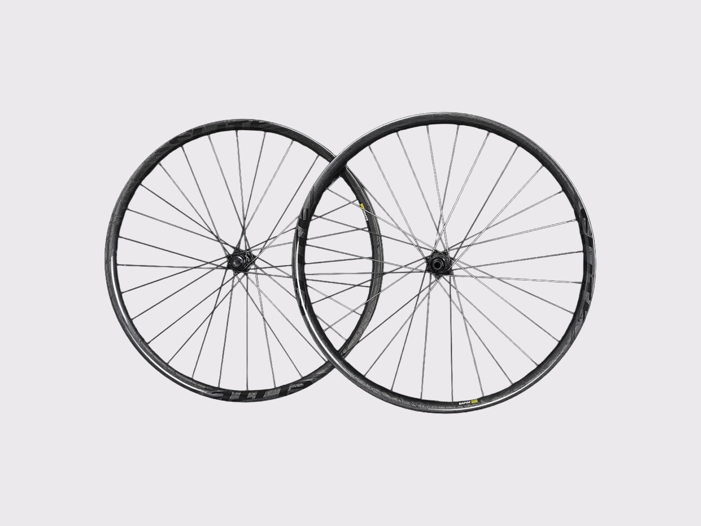 Paire de roues VTT 29 pouces Elitewheels Pro36 en carbone marbré avec rayonnage asymétrique Sapim CX-Ray sur fond neutre.