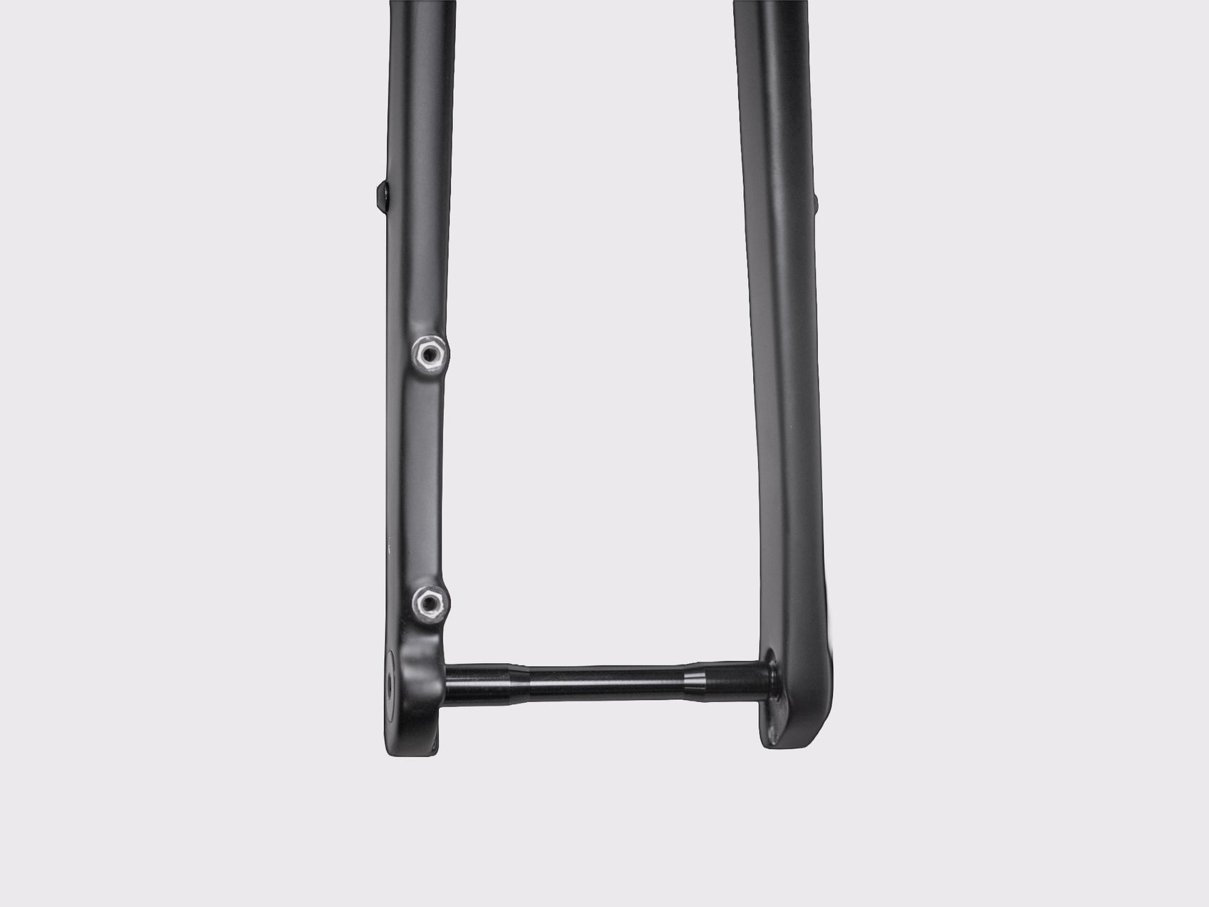 Détail macro sur la patte de fourche inférieure montrant l'interface de l'axe traversant et les deux inserts filetés inférieurs pour accessoires.
