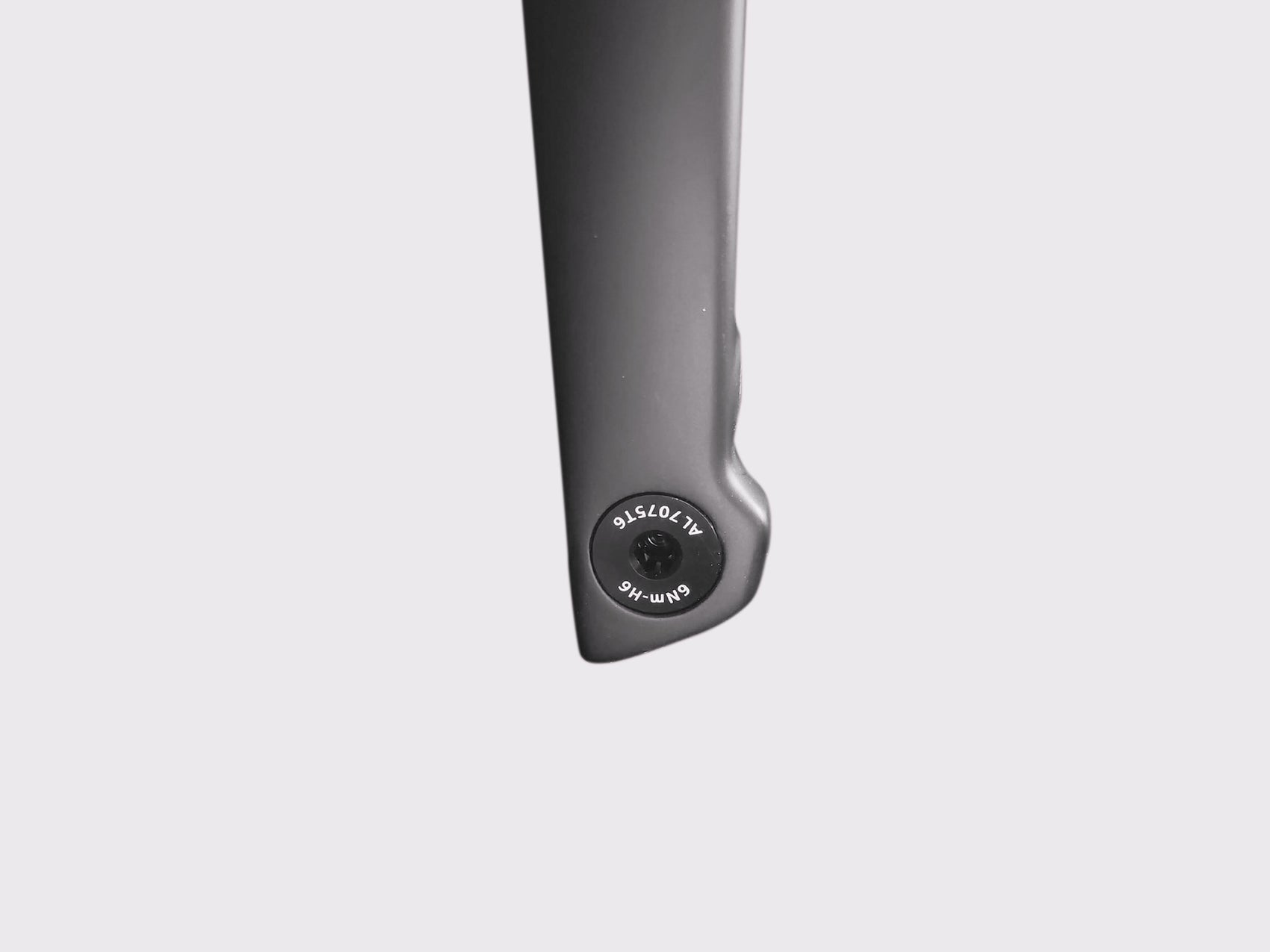 Gros plan sur l'axe traversant affleurant en aluminium 7075-T6. Marquages techniques visibles : couple de serrage 6Nm et empreinte H6.