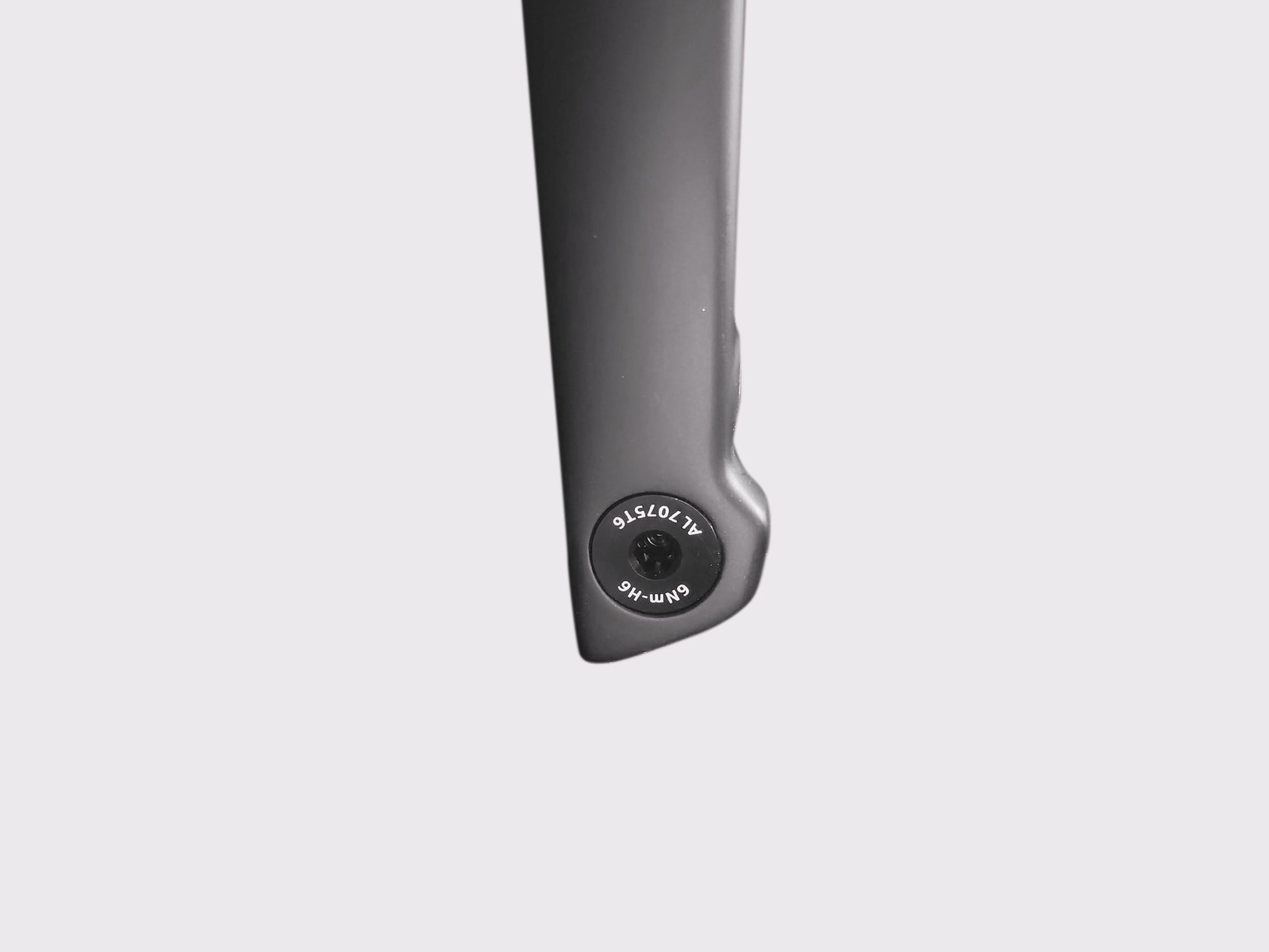 Gros plan sur l'axe traversant affleurant en aluminium 7075-T6. Marquages techniques visibles : couple de serrage 6Nm et empreinte H6.
